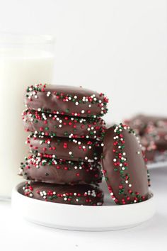 chocolate covered cookies with sprinkles and a glass of milk on the side