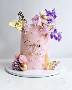 a pink cake decorated with flowers and butterflies