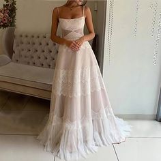 a woman standing in front of a couch wearing a white dress with lace on it