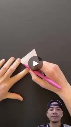 two hands holding a pink toothbrush over another person's face