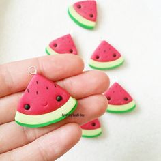 a person holding a tiny watermelon slice in their hand with other pieces around them