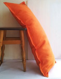 an orange pillow sitting on top of a wooden stool