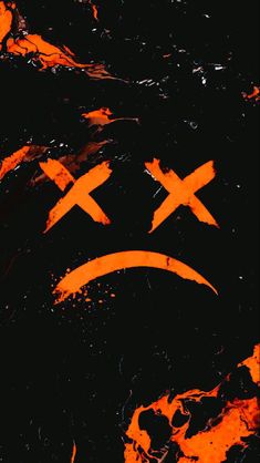 an orange smiley face drawn on the side of a black wall with paint splattered over it