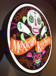 the mexican kitchen sign is decorated with sugar skulls and colorful decorations on it's side