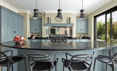 a kitchen with blue cabinets and an island in the middle, surrounded by bar stools