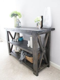 a wooden table sitting in the middle of a living room next to a white wall