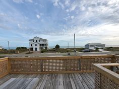 a wooden deck with an ocean view in the back ground and houses on the other side