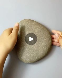 someone is placing a rock on the wall with their thumb and thumb pressing it up