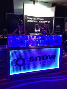 people sitting at a table with snow logo on the front and blue lights behind it