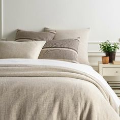 the bed is made with linens and pillows, along with a potted plant