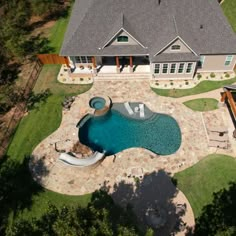 an aerial view of a house with a swimming pool in the foreground and landscaping around it