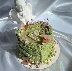 there is a green cake with flowers and angel decorations on the top, sitting on a white table cloth