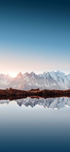 the mountains are reflected in the still water