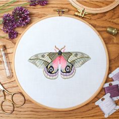 a close up of a embroidery on a wooden table with scissors and other crafting supplies