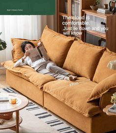 a woman laying on top of a couch reading a book