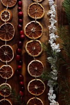 dried oranges, cherries and pine cones are arranged on a wooden table with christmas decorations