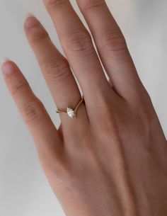 a woman's hand with a diamond ring on top of her left hand,