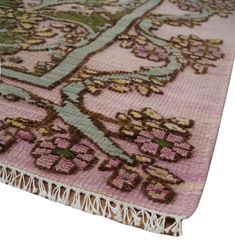 a pink rug with an intricate design on the bottom and fringes around the edges