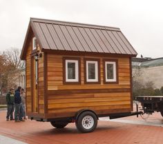 a tiny house on wheels with people standing around