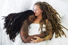 two women laying in bed with dreadlocks on their heads and one is hugging the other