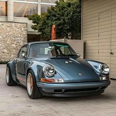 a blue porsche parked in front of a building