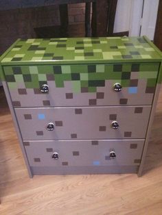 a dresser that has been painted with green and gray squares on it, sitting on a wooden floor