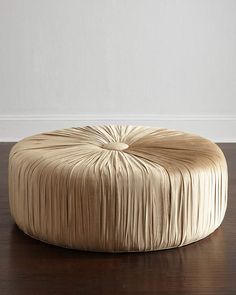 a large round ottoman sitting on top of a wooden floor next to a white wall