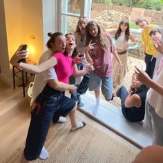 a group of young women standing around each other in front of a window with their arms out