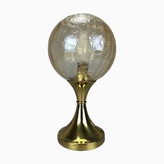 a glass ball sitting on top of a brass stand with a white background in the middle