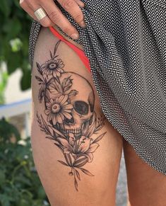 a woman with a skull and flowers tattoo on her thigh