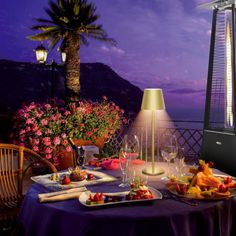 a table with food and wine on it in front of an ocean view at night