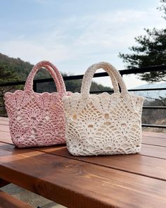 two crocheted bags sitting on top of a wooden table next to each other