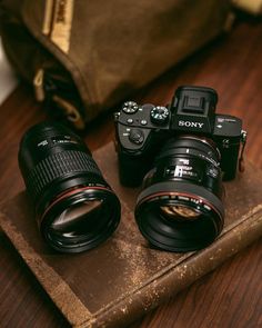 two cameras sitting on top of a wooden table