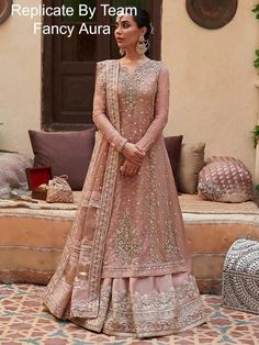 a woman standing in front of a building wearing a pink lehenga and matching jewelry