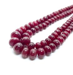 three strands of red glass beads on a white surface