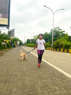 a woman is walking her dog down the street