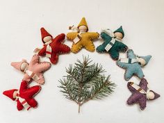 an assortment of felt ornaments arranged in a circle on a white surface with pine needles