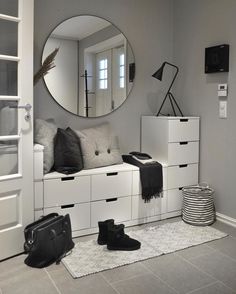 a room with white furniture and a round mirror on the wall