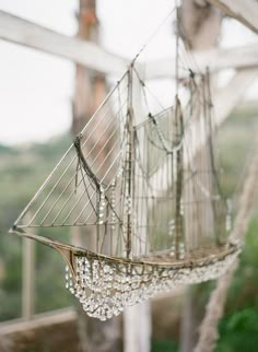 an old sailboat is hanging from the ceiling in front of a window with glass beads on it