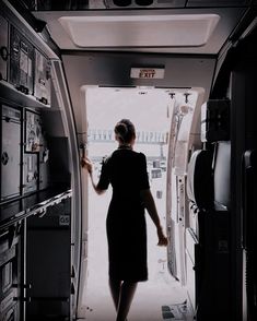 a woman in a black dress walking into an airplane