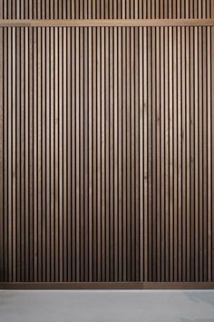 an empty chair sitting in front of a wooden wall with vertical slats on it