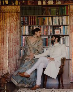 a man sitting next to a woman in front of a book shelf filled with books