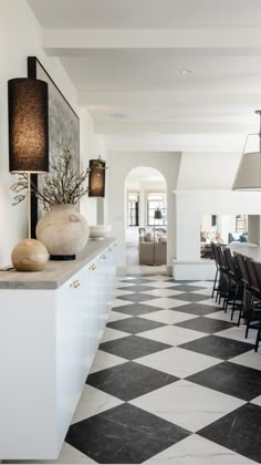 an elegant dining room with black and white checkered flooring, chandelier, vases and lamps