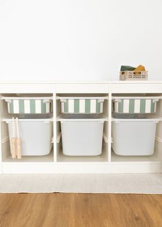 a white shelf filled with plastic containers on top of a hard wood floor