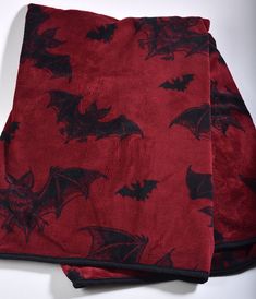 two red and black bat patterned towels on a white tablecloth with one folded over the other