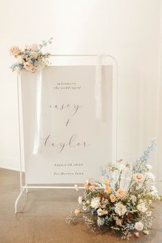 a wedding sign with flowers on it and a bouquet of flowers in front of it