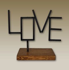 a metal sculpture with the word love spelled in it's letters on a wooden base