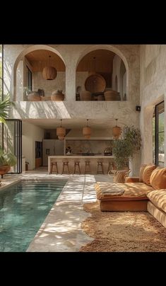 a living room filled with furniture next to a swimming pool in the middle of a house