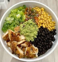 a white bowl filled with lots of different types of food on top of a wooden table