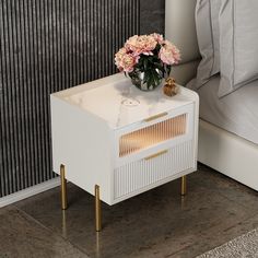 a white nightstand with flowers on it next to a bed